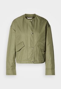 Veste à manches longues vert olive clair avec boutons-pression à l'avant et deux poches avant à rabat, présentée sur fond blanc.