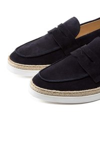 Marineblaue Wildlederloafer mit einer geflochtenen Jutesohle, ausgestattet mit einer flachen weißen Gummizwischensohle und einem dekorativen Riemen über dem Obermaterial.