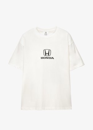Biała koszulka z krótkim rękawem z czarnym logo Hondy i napisem na środku klatki piersiowej, przedstawiona na jednolitym tle.