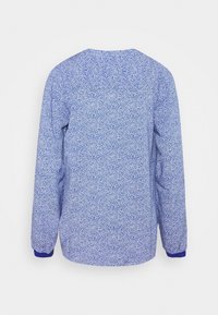 Pull bleu à manches longues avec un motif à pois blancs et des poignets bleus unis, vu de dos sur fond blanc.
