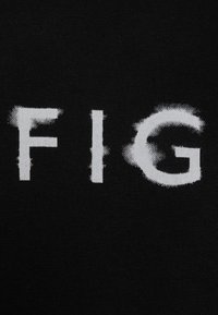 Černá tkanina s nápisem "FIG" vytištěným bílou barvou, s opotřebovanou texturou a nejednotnými okraji, zaměřená na písmo.