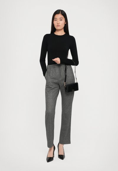 Black long-sleeve top, gray check-patterned trousers, black patent handbag, and pointed black heels. Tailored fit with a high waist.