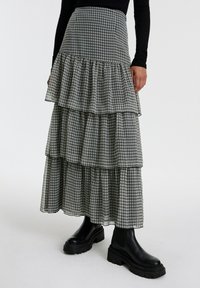 Zwart-wit geruite tiered maxi rok met ruches, gemaakt van lichtgewicht stof, gecombineerd met stevige zwarte enkellaarsjes.