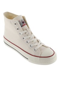 Hoge canvas sneakers in lichtbeige met een witte rubberen neus, zilveren oogjes en een rode streep langs de zool. Klassieke branding op de tong.