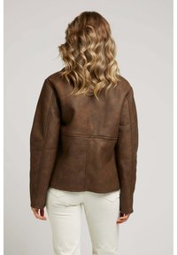 Veste en cuir marron avec un design ajusté, coutures visibles et manches longues, présentée de dos sur un fond neutre.