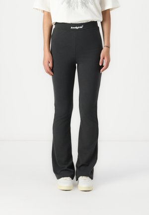 Black flared pants with elastic waistband featuring a logo tag. Material appears soft and stretchy, designed for a fitted silhouette.