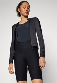 Black cycling outfit featuring a sleeved, zippered jacket and fitted shorts. Made from smooth, stretchy fabric with ergonomic seams and padding.