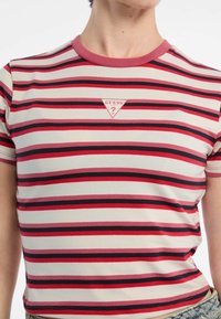 Pasiasty t-shirt z bawełny w kolorze białym, czerwonym i czarnym. Posiada okrągły dekolt oraz małe trójkątne logo na środku. Krótkie rękawy.