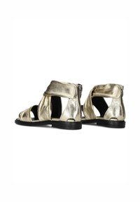 Metalen gouden sandalen met een open ontwerp, die gekruiste banden en een achterrits tonen. Gehard leder en zwarte zolen.