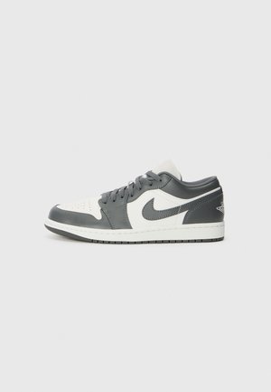 Zapatilla Nike Air Jordan de caña baja en cuero blanco y gris oscuro con cordones grises y el característico logo Nike swoosh en el lateral.