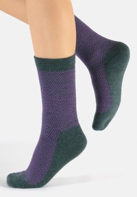 Calcetines de lana en verde oscuro con un patrón de espiga púrpura. Hasta el tobillo, con un puño acanalado y áreas de talón y puntera reforzadas.