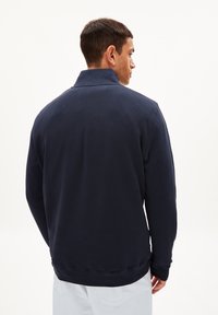 Marineblauwe sweatshirt met hoge kraag, ribgebreide manchetten en een textuurafwerking, met een effen kleur en een ontspannen pasvorm.