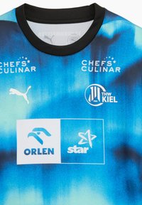 Kortärmad blå sporttröja med gradientdesign, svart krage och logotyper för Puma, Chefs Culinar, THW Kiel, Orlen och Star.