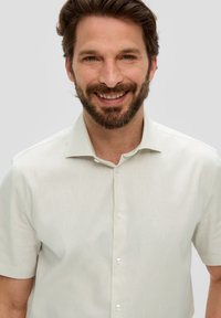 Koszula z krótkim rękawem, jasnobeżowa, zapinana na guziki, o miękkiej fakturze i klasycznym kołnierzyku, z perłowobiałymi guzikami i gładkim wykończeniem.