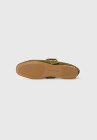 Green suede flat shoe with a rounded toe and a small buckle detail. The sole is beige rubber with textured grooves for grip.