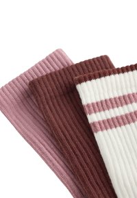 Tre paia di calzini a coste: rosa pastello, marrone scuro e crema con strisce rosa. Materiale a maglia strutturata, con larghezze variabili nel design.