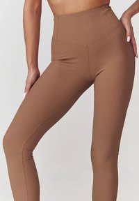 Brązowe legginsy z wysokim stanem, wykonane z żebrowanej tkaniny, o dopasowanym kroju i bezszwowej konstrukcji, zapewniające gładki wygląd.