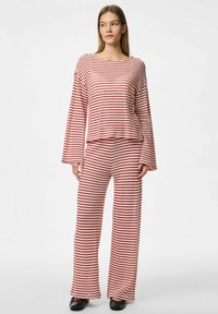 Completo da lounge a righe rosse e bianche con un top lungo e largo e pantaloni a gamba larga, caratterizzato da una texture morbida e un design rilassato.