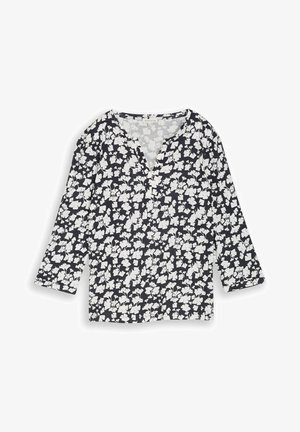 Zwart-witte bloemenblouse met lange mouwen, een ronde hals en knoopdetail aan de voorkant, plat gelegd op een witte achtergrond.