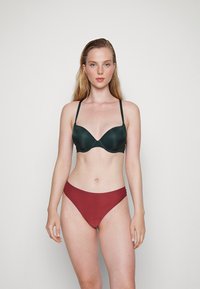 Sutiã acolchoado verde escuro com alças finas e decote em V, combinado com calções de biquíni bordeaux de cintura alta, textura suave.