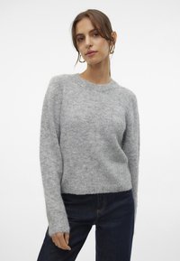 Gray knitted sweater with a round neckline, long sleeves, and a soft, fuzzy texture, paired with dark blue jeans.