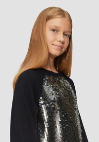 Schwarzer Sweatshirt mit einem großen Paillettenmotiv in Silber- und Goldtönen auf der Vorderseite. Weicher Stoff mit lockerer Passform und Raglanärmeln.
