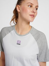 Hvid T-shirt med lysegrå raglanærmer, med et lilla logo på brystet. Blødt bomuldsblandingsmateriale og afslappet pasform.