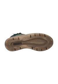 Suela de zapato verde con goma texturizada, que presenta un patrón en zigzag para un mejor agarre. Incluye un detalle de marca en el costado y una entresuela sólida beige.