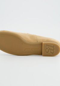 Chaussure en daim beige avec un bout arrondi et une semelle en caoutchouc lisse. Présente un marquage en relief sur la semelle et un design minimaliste.