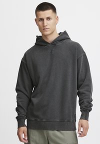 Dunkelgrauer Hoodie aus weichem Stoff, mit einer großzügigen Kapuze, gerippten Bündchen und einem gerippten Saum mit einem Logodetail nahe dem unteren Ende.