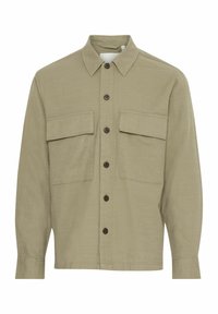 Chemise verte à boutons faite d'un tissu texturé, dotée d'un col, de deux poches poitrines et de boutons marron. Manches longues avec poignets à boutons.