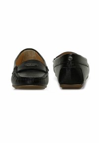 Mocassins en cuir noir avec une surface texturée, un bout rond et une semelle en caoutchouc profil bas. Comprend des coutures décoratives et des accents de logo.