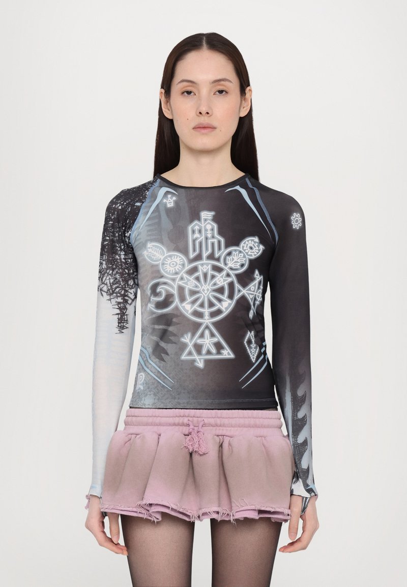 Long-sleeve black and blue graphic top featuring abstract designs and symbols; paired with a frayed, light pink pleated skirt.