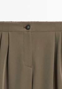 Olive green trousers with a smooth texture, featuring pleats, a button closure, and a side pocket. Designed for a fitted silhouette.