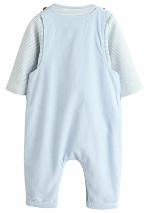 Salopette en velours côtelé bleu clair avec un t-shirt à rayures à manches longues en dessous. Dispose de boutons sur les bretelles et de poignets retroussés. Texture douce.
