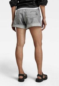 Pantalones cortos de denim gris con puños doblados, que cuentan con dos bolsillos traseros y una marca mínima. Fabricado con un tejido duradero y de textura suave, con un diseño casual.