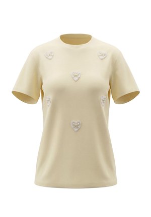 Kortærmet, lysegul T-shirt med seks hvide blondehjerteapplikationer på bryst og skuldre, vist mod hvid baggrund.