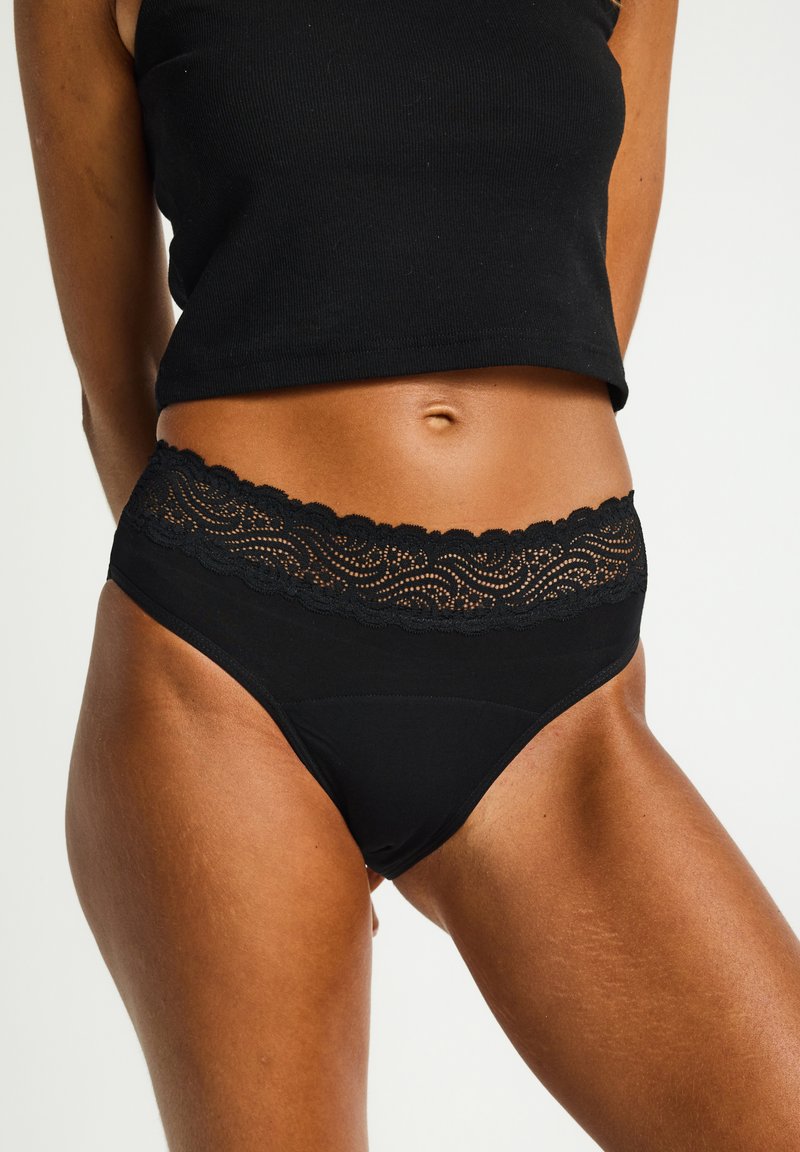 Culotte noire bordée de dentelle avec un motif floral le long de la taille. Tissu doux avec une texture lisse et une coupe classique.