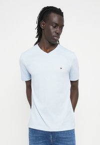 Φωτεινό γαλάζιο μπλουζάκι με V-λαιμόκοψη και κοντά μανίκια, κατασκευασμένο από μαλακό ύφασμα. Διαθέτει μικρό λογότυπο στο στήθος και χαλαρή εφαρμογή.