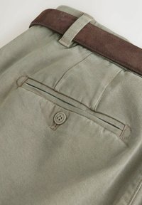 Grüne Baumwollhosen mit einem braunen Wildlederbund, einer Gesäßtasche mit Knopfverschluss und subtiler gerippter Textur.
