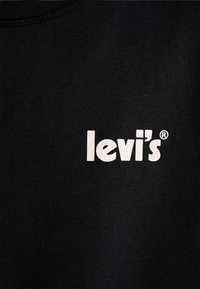 T-shirt en coton noir avec un grand logo "levi's" blanc. Encolure côtelée et texture lisse sur tout le tissu.