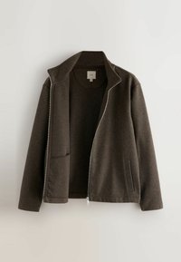 Hnedá bundová mikina na zips vyrobená z mäkkej tkaniny, s vystúpeným golierom, prednými vreckami a čistým, minimalistickým dizajnom. Viditeľné vystužené švy.