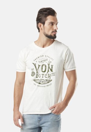 T-shirt en coton blanc avec col rond, manches courtes, présentant un design vintage imprimé en vert avec le texte "Von Dutch" et des détails de logo.