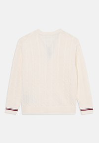 Kremfarget kabelstrikket genser med lange ermer, ribbestrikkede mansjetter med røde og marineblå striper, V-hals bak og texturert overflate.