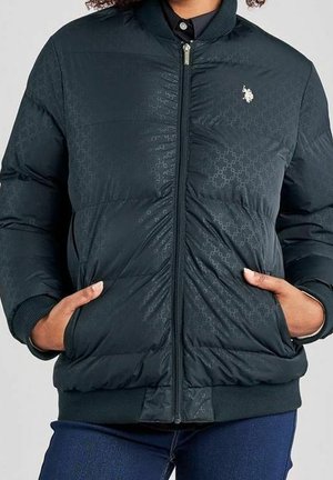Veste matelassée noire zippée avec un motif géométrique subtil, poignets et ourlet côtelés, et mains dans les poches latérales.