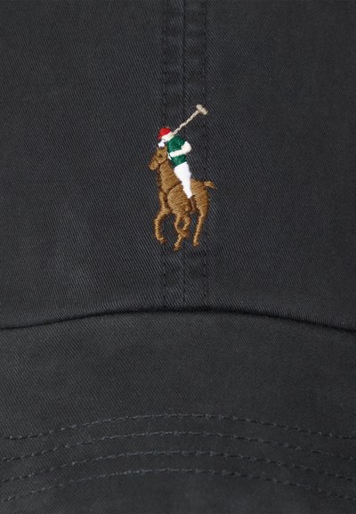 Bestickte Figur eines Polospielers mit rotem Helm und grünem Hemd, der auf einem braunen Pferd auf schwarzem Stoff reitet.