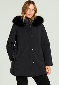 Sort vandtæt frakke med falsk pelskrave, der har knapper foran, sidelommer og en afslappet pasform. Glat tekstur.