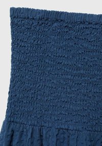 Navy blue fabric skirt with smocked texture at the top and gathered ruffles at the bottom, creating a tiered design.