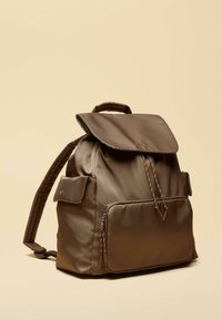 Rjav nahrbtnik iz najlona z zaponko na preklopu, sprednjim žepom na zadrgo, pletenimi vrvicami za zapiranje in oblazinjenimi naramnicami. Gladek videz, minimalistična zasnova.