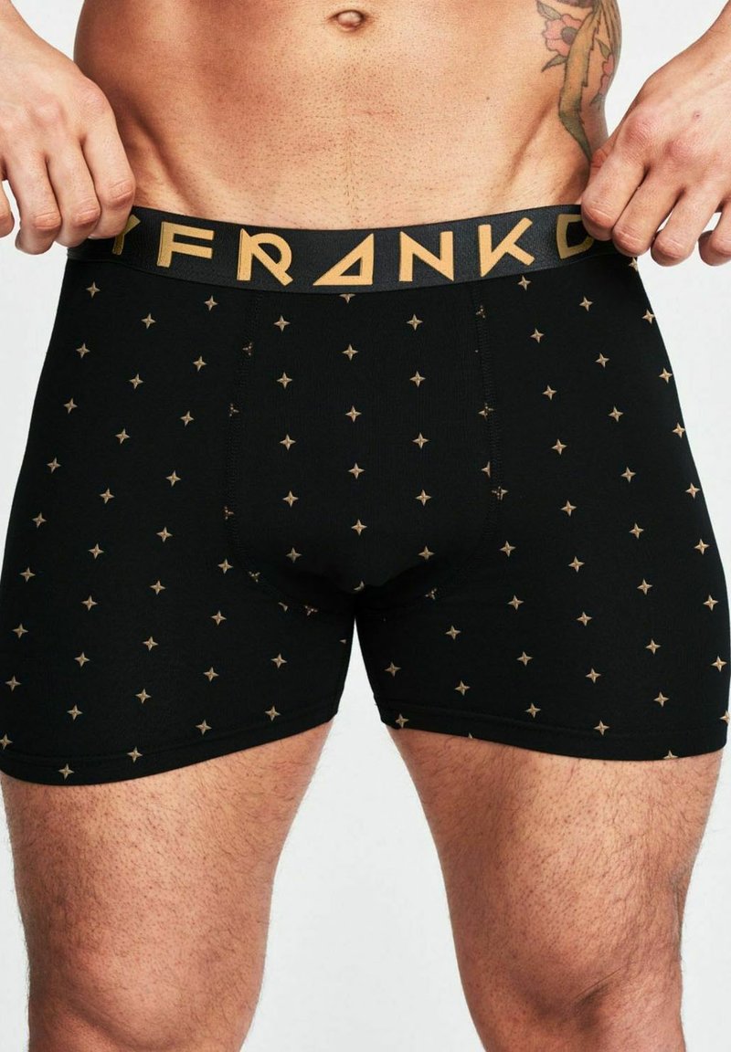 Svarta boxershorts med ett mönster av guldstjärnor, elastisk midja med "FRANK" i svart och guld, tillverkade av ett slätt, stretchigt material.